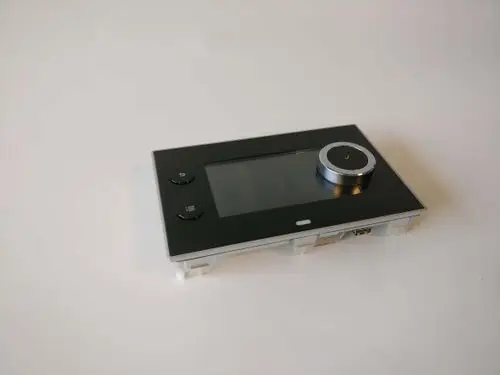 Touchscreen-Steuergerät von Remeha mit rundem Drehknopf und zwei Tasten auf der linken Seite. Der Bildschirm ist flach und zeigt keine spezifischen Informationen.